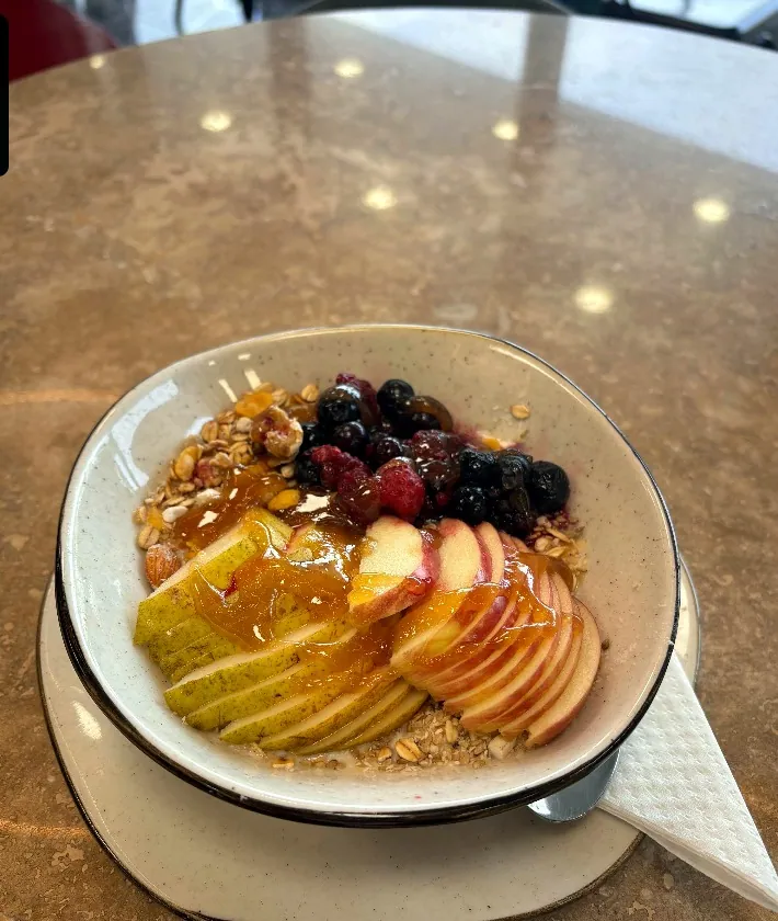 Bowl de frutas frescas con café junto a la ventana